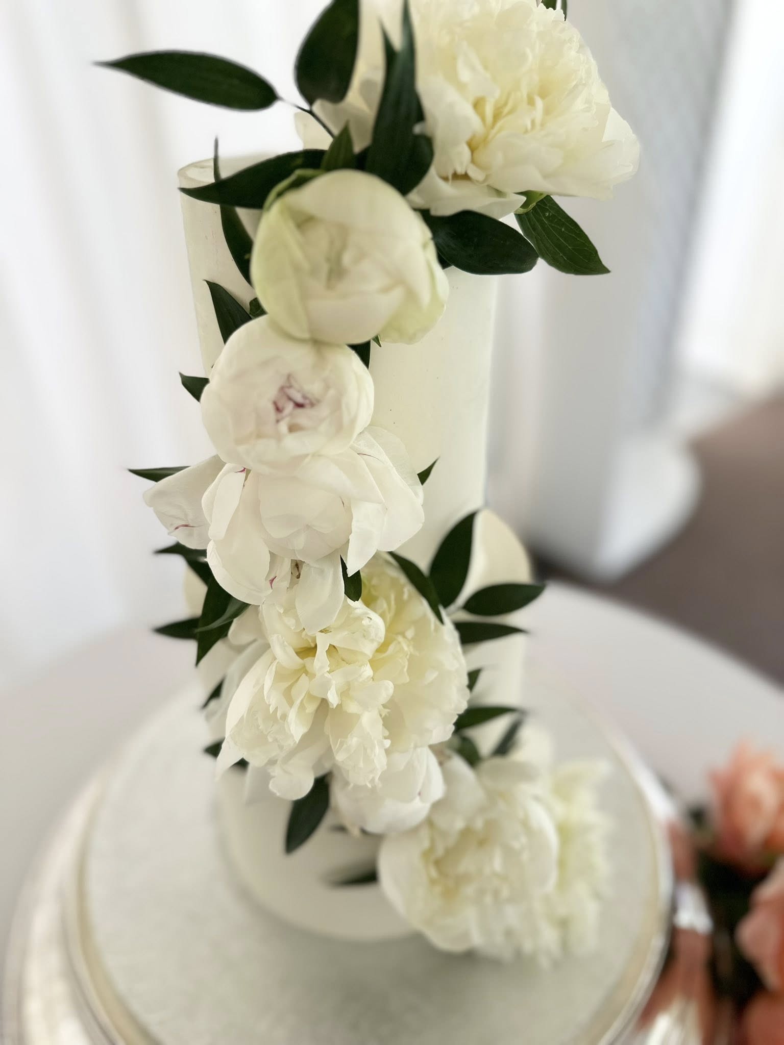 Elegant white tiered wedding cake with peony flowers