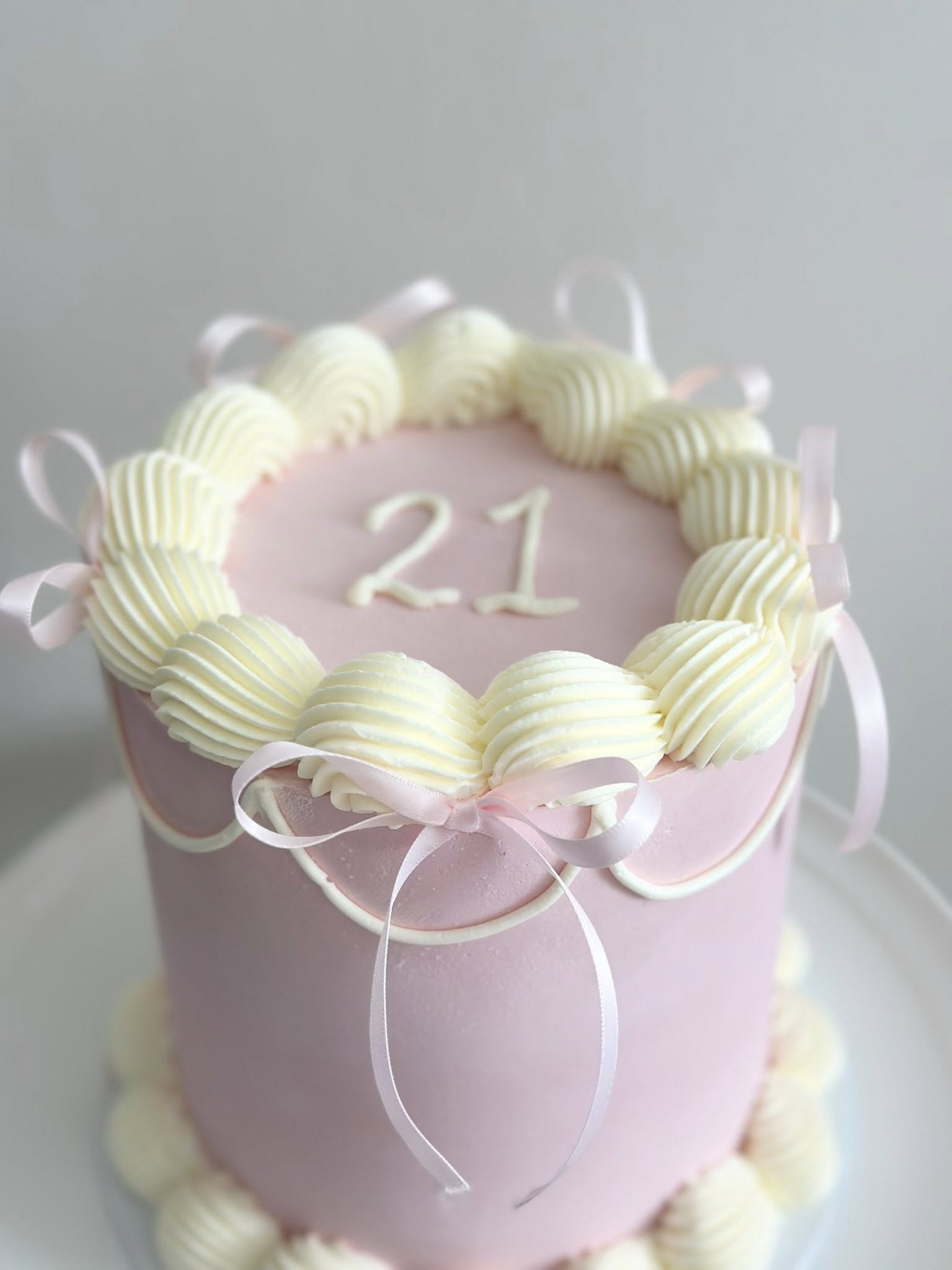 Pink birthday cake with number 21 and cream piping